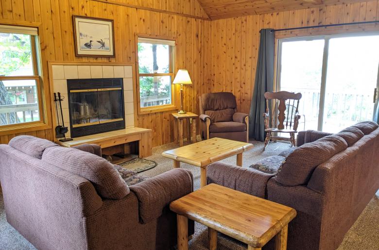 Living room with couch, loveseat, recliner, wood burning fireplace and patio door to the deck.