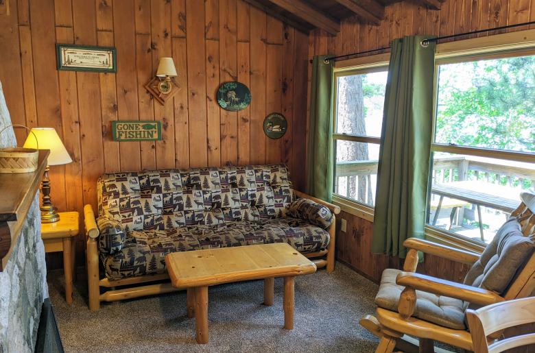 Living room with futon, chair, and wood burning fireplace.